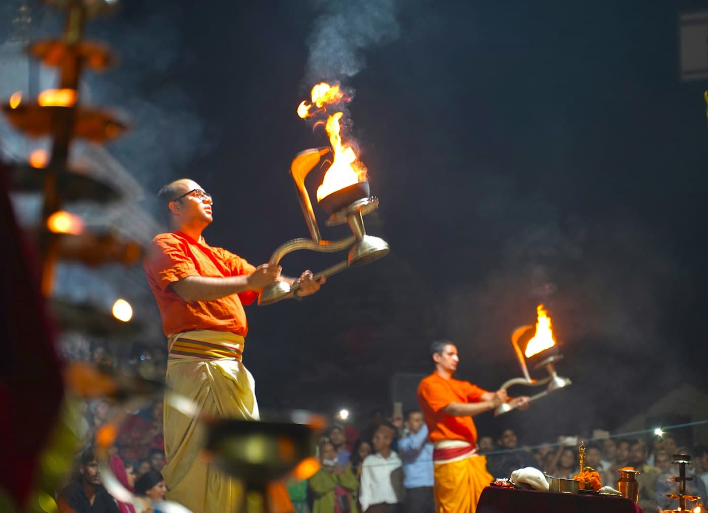 Priest in white garments raising a ceremonial fire offering