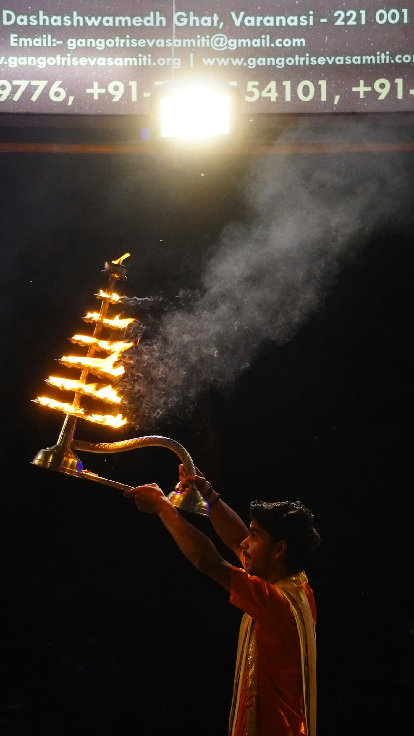 Close view of a priest holding a lit diya during ceremony