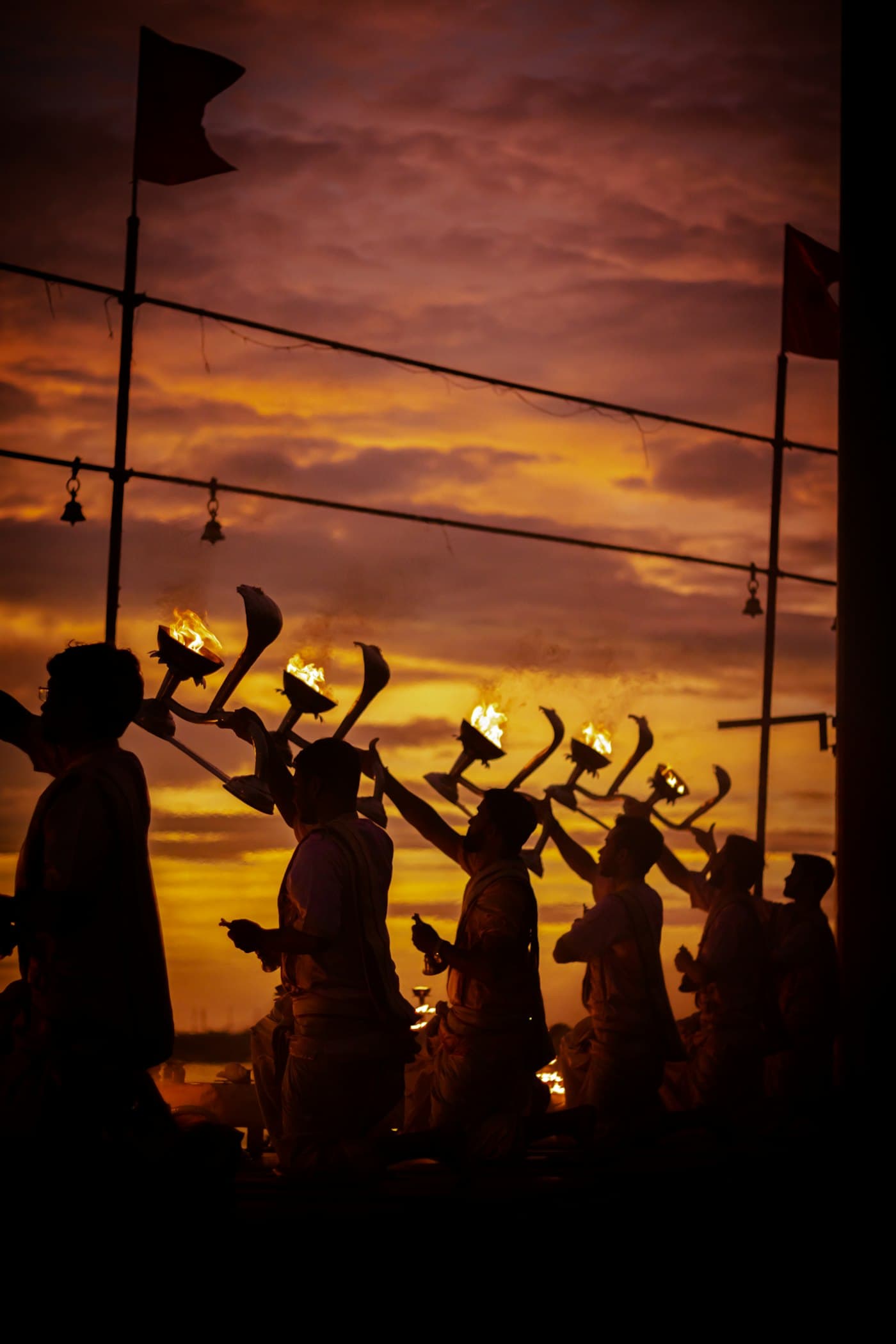 Silhouettes holding ceremonial flags against evening light