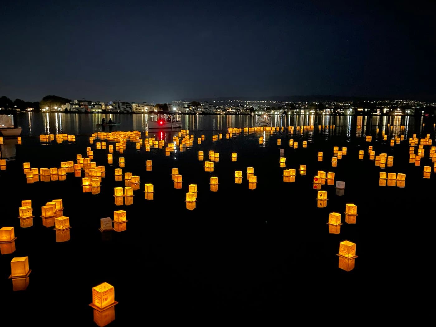 Lanterns and lights floating on dark water at night