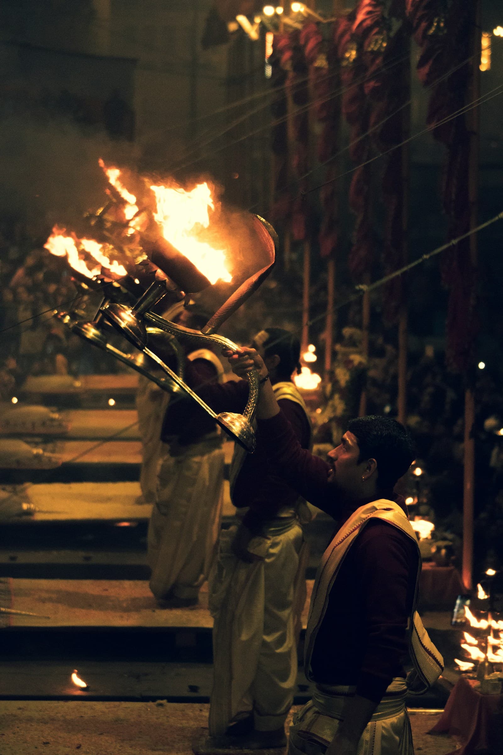Priest lifting a flaming aarti lamp during the evening ceremony at Dashashwamedh Ghat