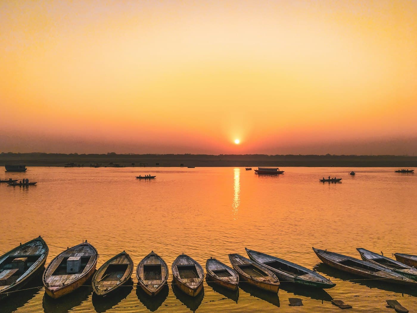 Boats on the Ganges silhouetted against a warm dusk sky